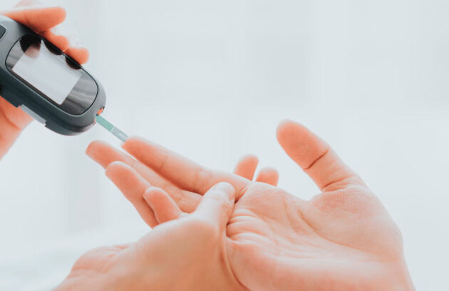 Mão aferindo o nível de açúcar no sangue e nível de diabetes