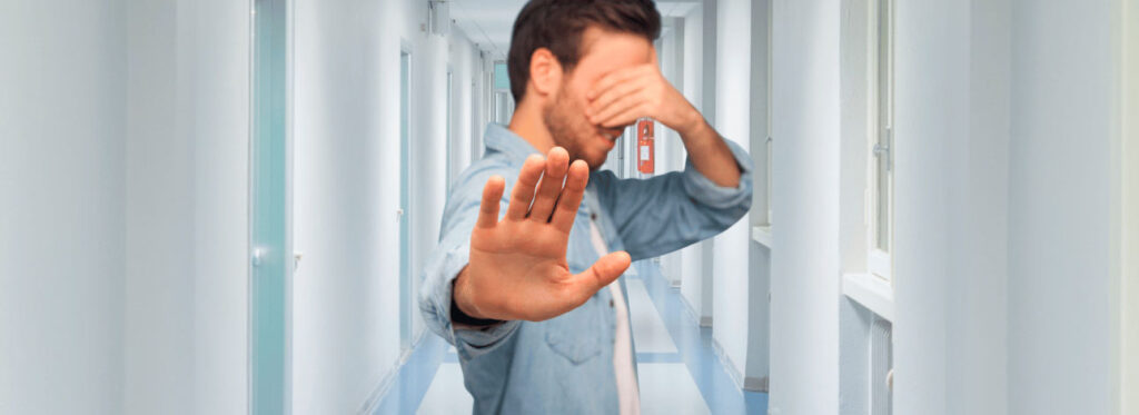 Homem com a mão no rosto fazendo sinal com a mão, representando a negação de consulta médica