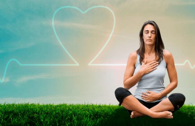 Mulher sentada na grama realizando meditação com um coração ao fundo