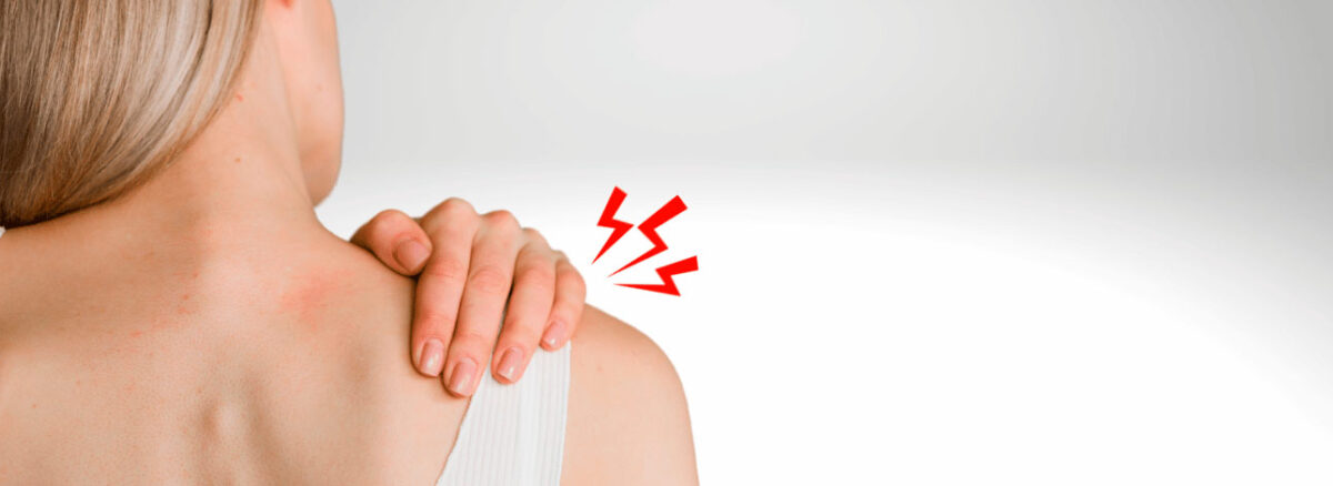 Mulher virada de costas com a mão no ombro direito, representando caso de fibromialgia