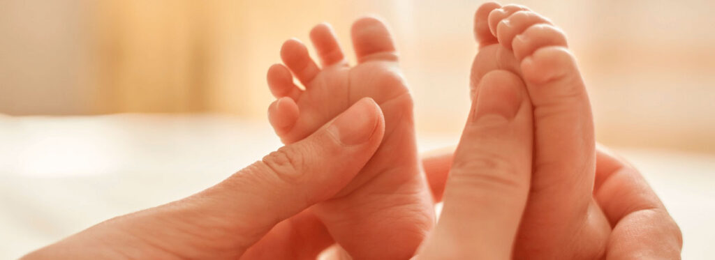 Mãos segurando pés de bebê recém-nascido