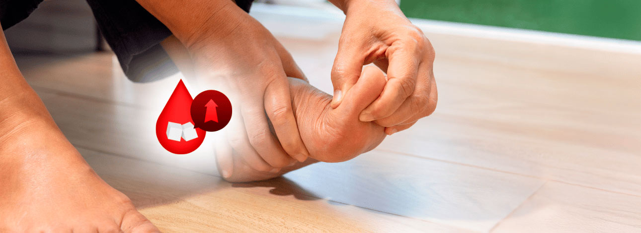 Pessoa com a mão no pé, indicando dor ou incômodo