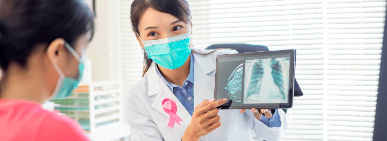 Médica mostrando a uma paciente o exame de mamografia