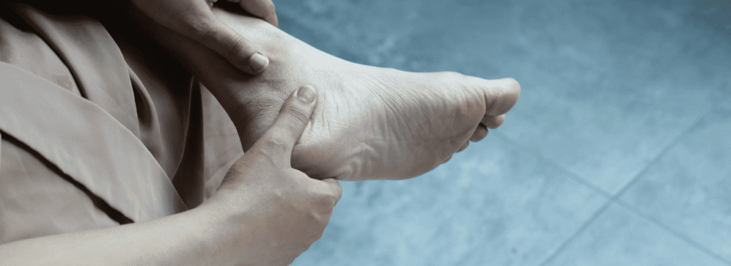 Pessoa com a mão no pé sofrendo com bolhas e calos