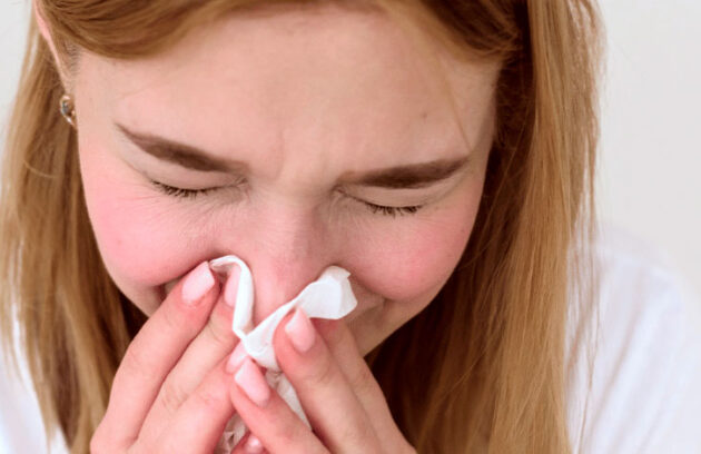 Mulher assoando o nariz