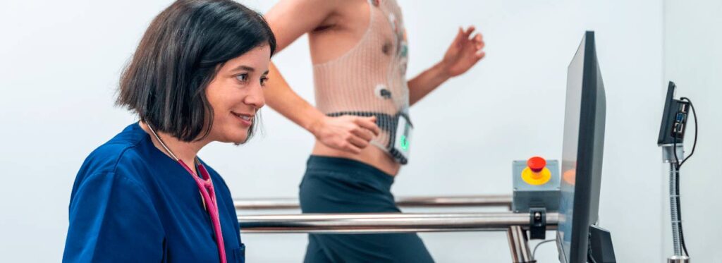 Paciente realizando exame de teste ergométrico, ou exame da esteira, enquanto médica faz avaliação