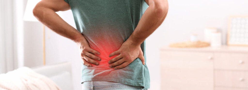 Homem com as mãos nas costas reclamando de dores