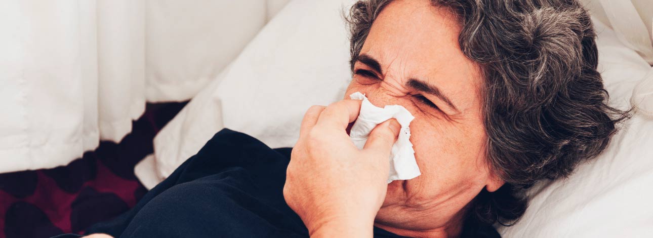 Mulher idosa gripada assoando o nariz