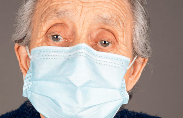 Mulher idosa com gripe utilizando máscara de proteção