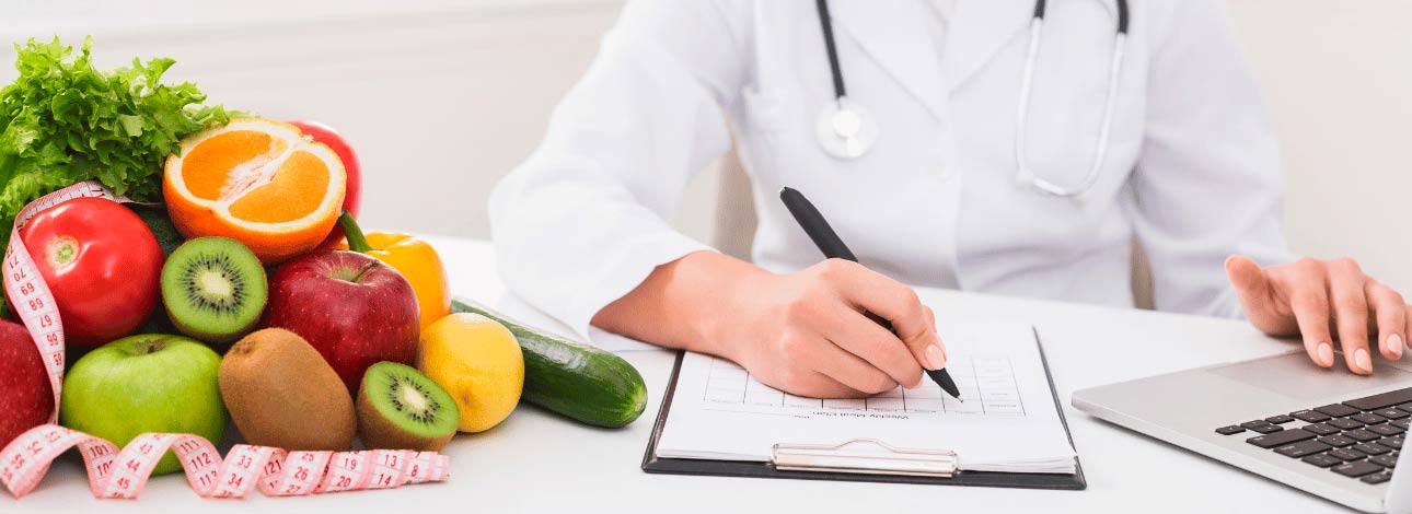 Nutricionista fazendo anotações referente à alimentação com alimentos ao lado