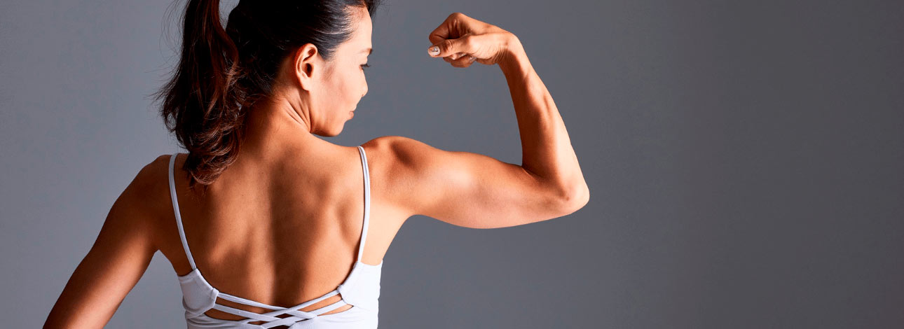 Mulher de costas flexionando o músculo do bíceps