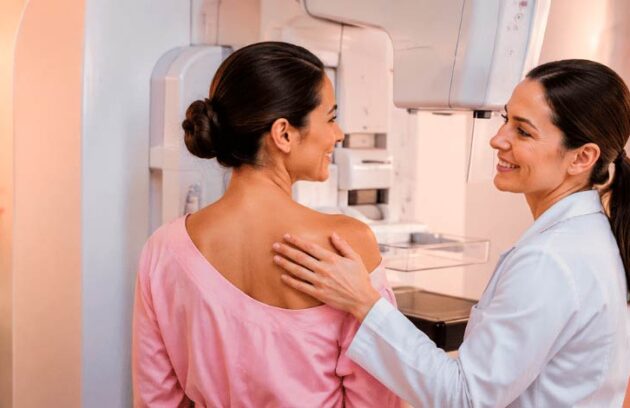 Paciente pronta para fazer o exame de mamografia ao lado de uma especialista