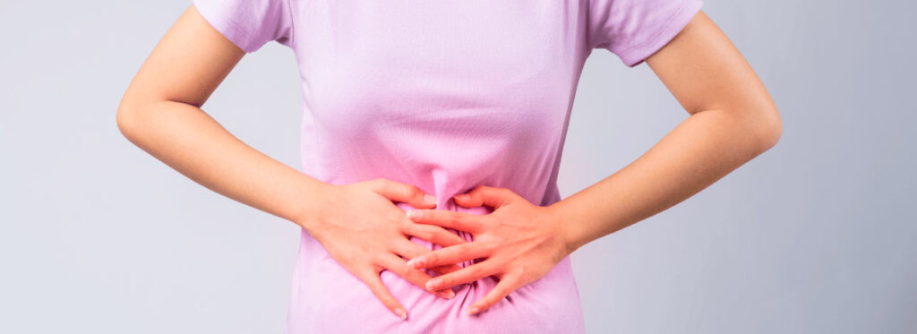 Mulher com as mãos na barriga com problema de constipação