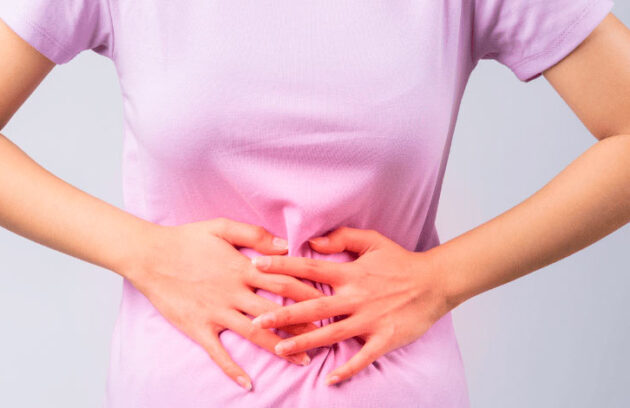 Mulher com as mãos na barriga com problema de constipação
