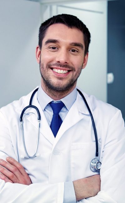 smiling doctor with stethoscope at hospital clinic, profession, people, health care and medicine concept - smiling doctor with stethoscope at hospital corridor